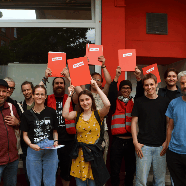 Elf Leute stehen vor der Geschäftsstelle in Gaarden und halten lächelnd Mappen mit dem Parteilogo hoch.