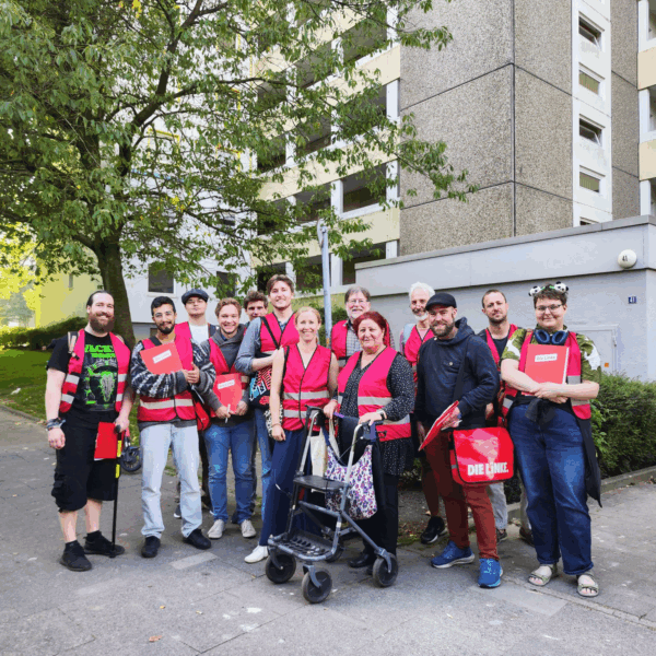Gruppe von Leuten in Parteiwesten vor einem Mettenhofer Wohnblock
