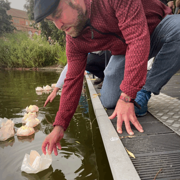 Björn Thoroe setzt eine papierne Lotosblüte mit teelicht auf den Kleinen Kiel