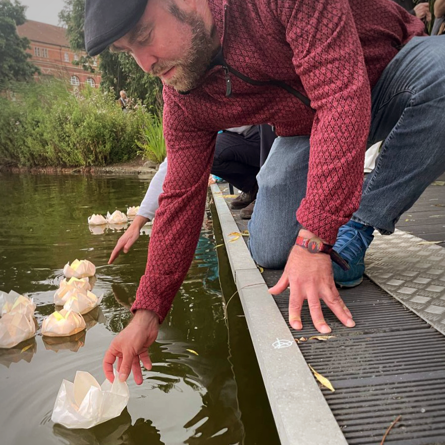 Björn Thoroe setzt eine papierne Lotosblüte mit teelicht auf den Kleinen Kiel