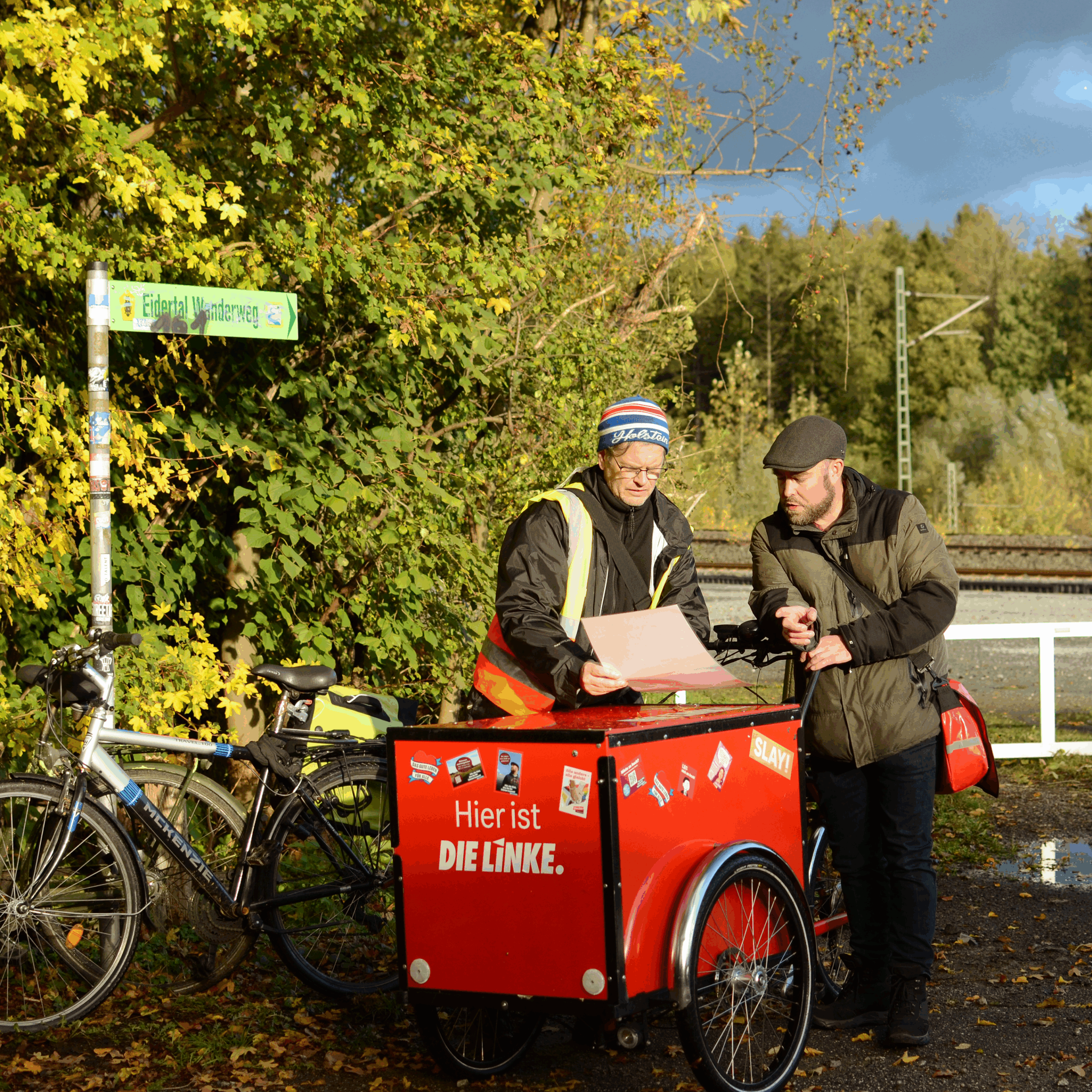 Niklas Hielscher und Björn Thoroe schauen sich eine Karte an, während sie am Hörn-Eidertal-Wanderweg stehen. Es ist ein sonniger Herbstmoment.